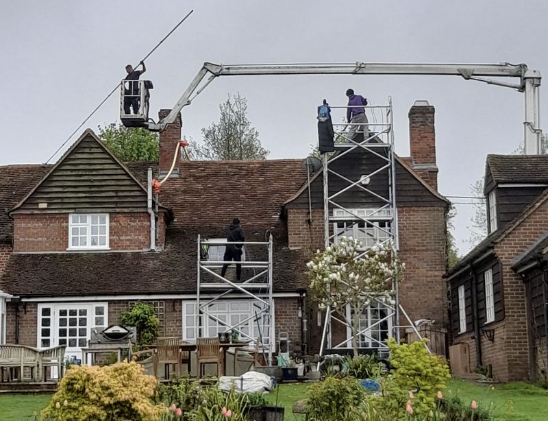 The Moss Cleaners using cherry picker and scaffolding to clean roof safely and professionally in Hersham, Surrey